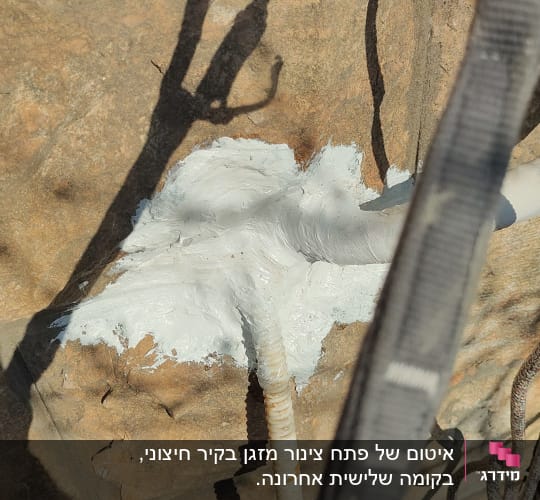 צינור לבן עם חומר איטום על קיר אבן